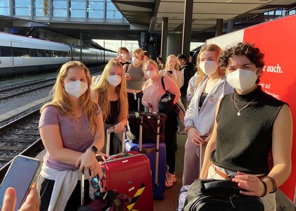 Elever med masker på en togstasjon - Klikk for stort bilde
